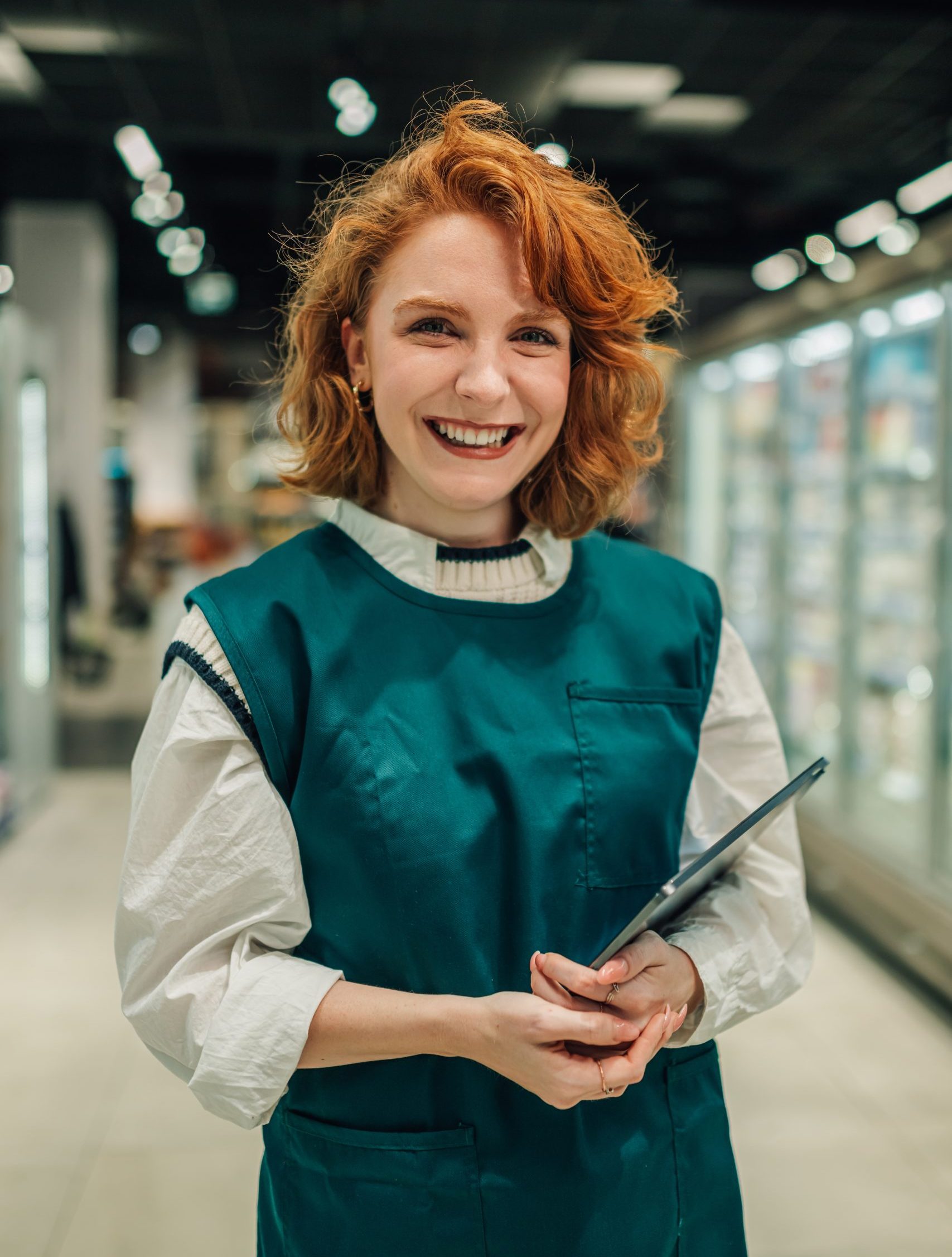 Smiling saleswoman holding tablet in supermarket aisle